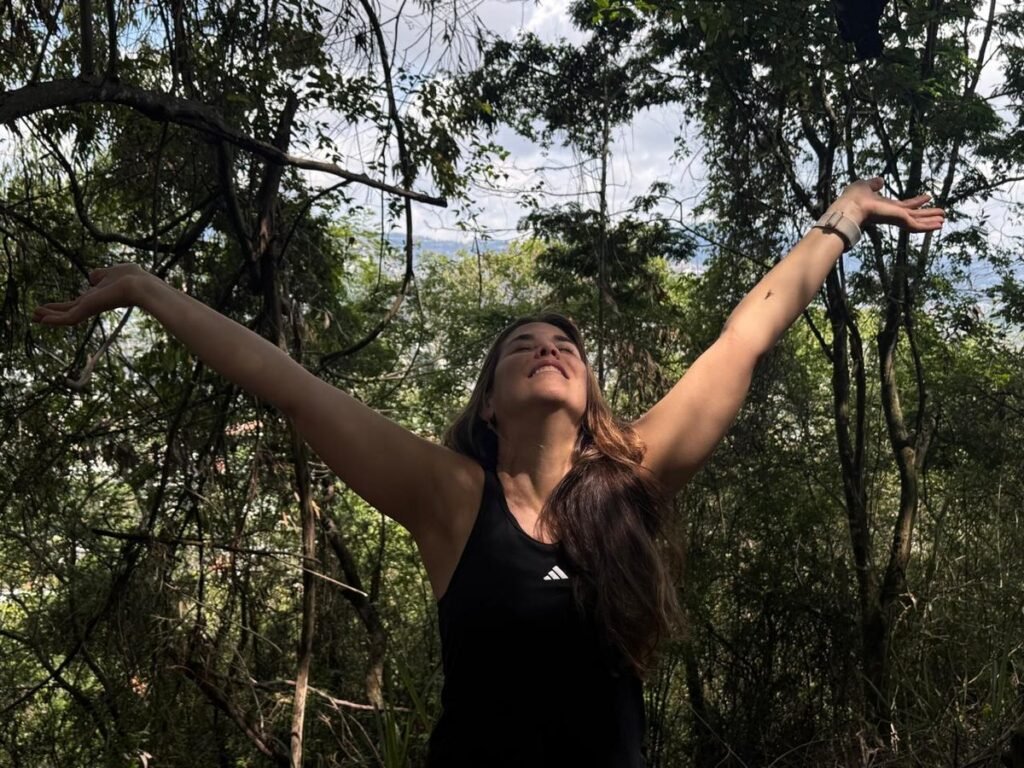 Mujer con los brazos abiertos en el bosque, símbolo de la felicidad después de los 40 y de elegir vivir con propósito