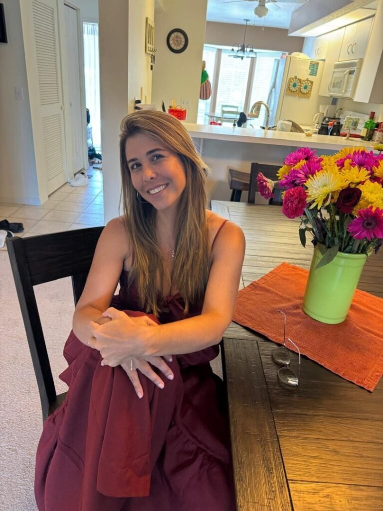 Mujer sonriendo sentada junto a un ramo de flores de colores, símbolo de volver a conectar consigo misma después de los 40